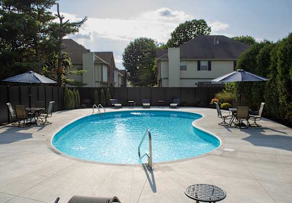 a swimming pool in a backyard with chairs and umbrellas