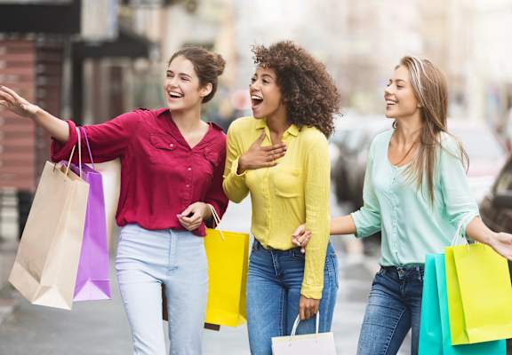 three women walking down the street with shopping bags