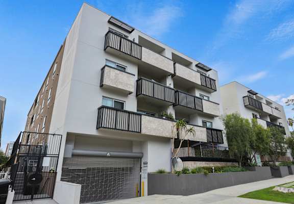 an image of a white apartment building with balconies and a garage door