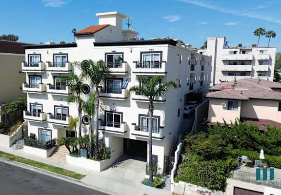 a large white apartment building with palm trees in front of it