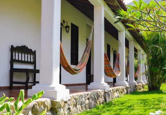 A porch with a bench and hammocks.