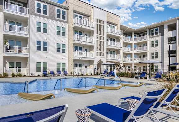 an apartment building with a swimming pool and lounge chairs