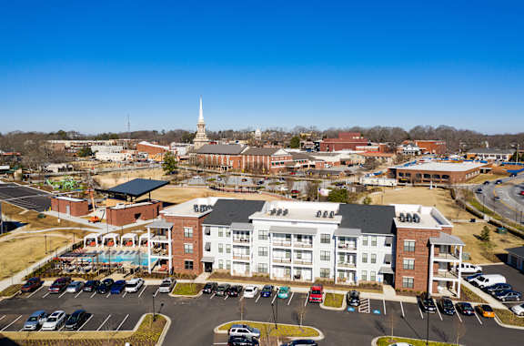 an aerial view of an apartment complex with a church steeple in the background at The Flats at Southlawn Apartments, GA