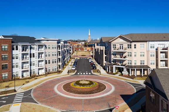 an aerial view of a street with a circular fountain in the middle at The Flats at Southlawn Apartments, Georgia