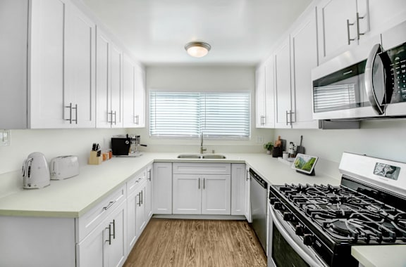 a kitchen with white cabinets and a stove and a microwave