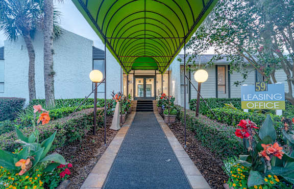 A long green covered walkway leads to a building with a sign that says "59 Leasing Office".
