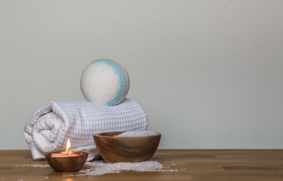 Bath bomb and towel on wood table with candle and salt
