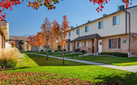 A row of houses with trees in autumn colors in front.