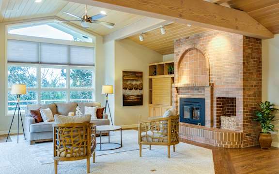 A living room with a fireplace and a ceiling fan.
