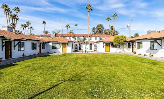a group of houses with a green lawn and palm trees