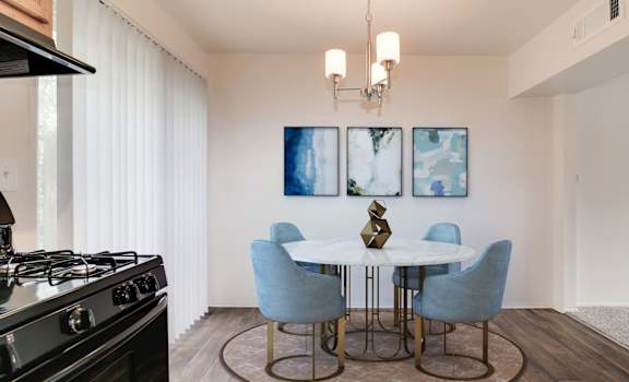 a dining area with a round table and four blue chairs at Courthouse Green Apartments, Chesterfield
