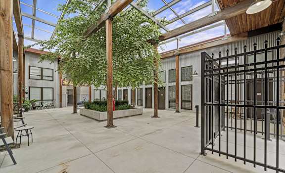 the courtyard of a building with a metal gate and trees