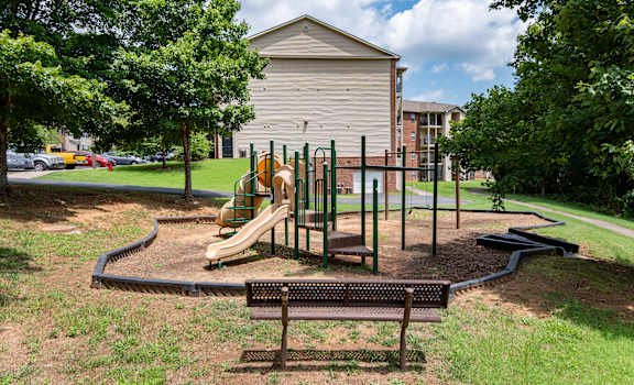 A playground with a slide, swings, and a bench.
