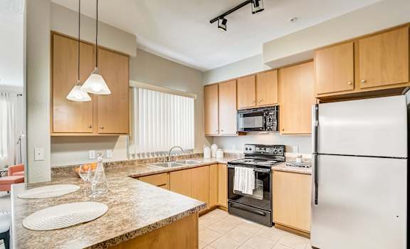 A kitchen with a refrigerator, oven, microwave, and sink.