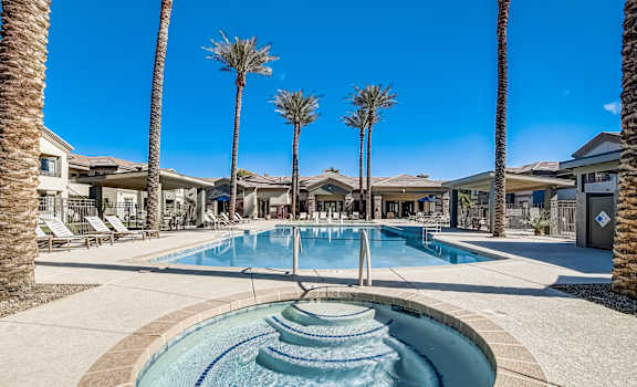 A pool surrounded by palm trees and a fountain in the middle.