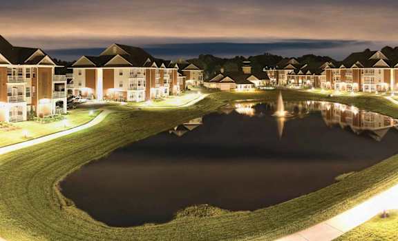an aerial view of a pond with houses around it at night