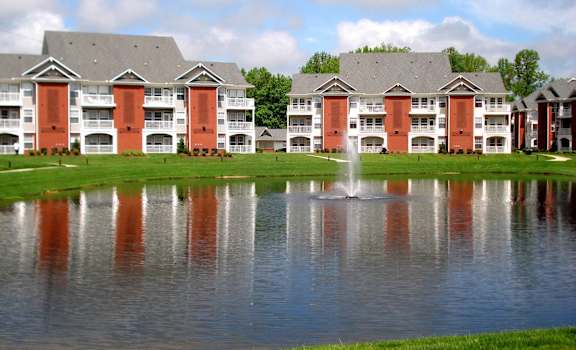 a lake with a fountain in front of an apartment building
