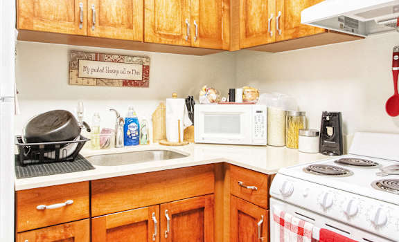Kitchen with white appliances, wood cabinetry, sink, and model decor