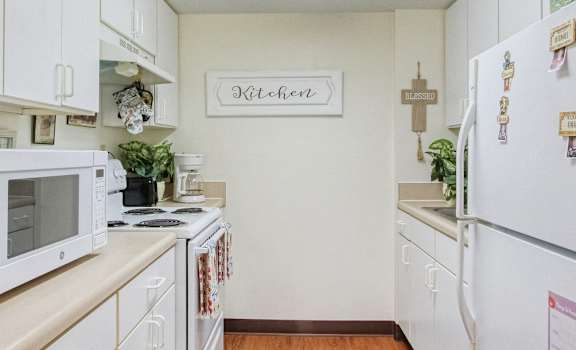 Residential kitchen with white cabinets and appliances at Holy Cross Manor I