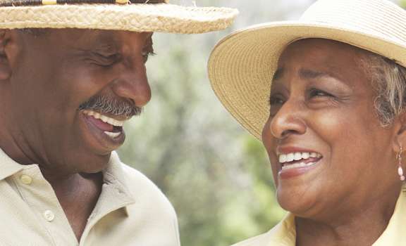 an older African American man and a woman wearing hats smiling at each other