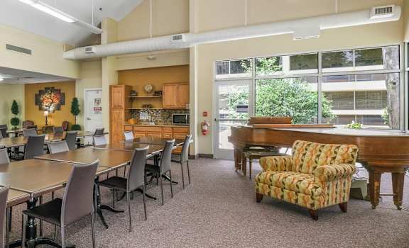 long rows of tables and chairs in community room with a grand piano