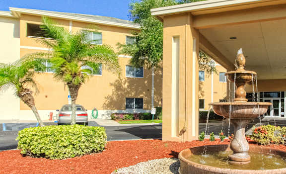 drive through entrance with lush landscaping and sparkling fountain