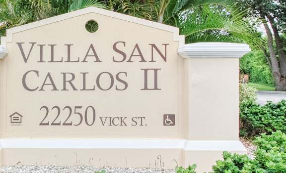 Monument sign with Villa San Carlos II and address in front of community