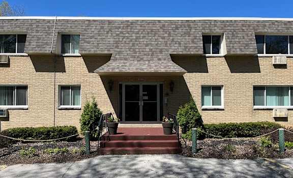 A building with a red carpet entrance and a small tree in front.