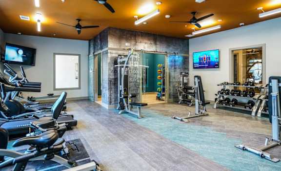 A gym with treadmills, exercise bikes, and a television.