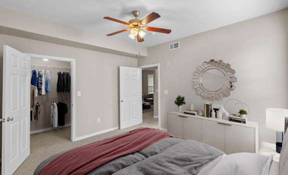 a bedroom with a large bed and a ceiling fan at The Clairborne Apartment Homes, Grand Prairie, TX, 75050