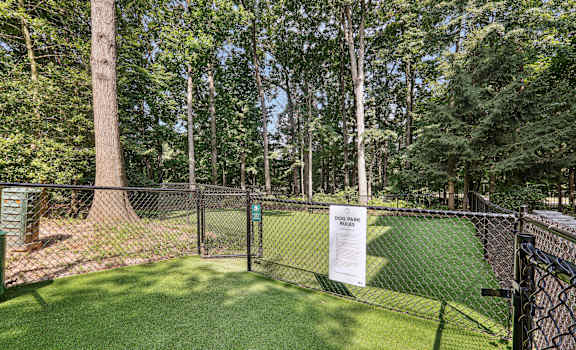 the dog park is fenced in with green grass and trees