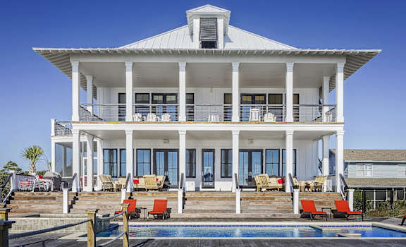 A white house with a pool in front.