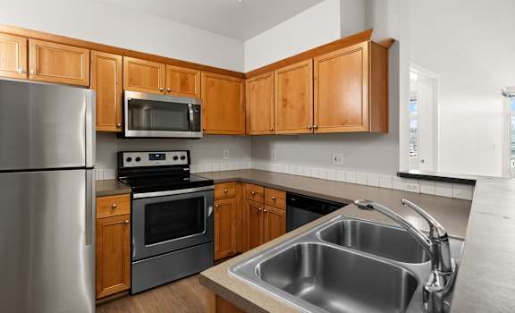 an empty kitchen with stainless steel appliances and wooden cabinets