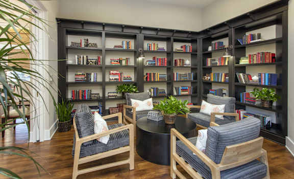 a seating area with chairs and a coffee table in front of a large bookshelf at 55+ Remington at Ladera Ranch, California, 92694