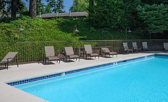 a swimming pool with chaise lounge chairs and trees in the background