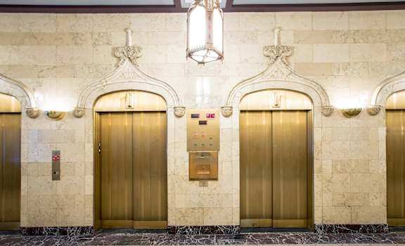 three elevators in a building with gold doors at The Equitable Building, Des Moines, IA, 50309