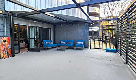 a patio with blue chairs and a red painting on the wall