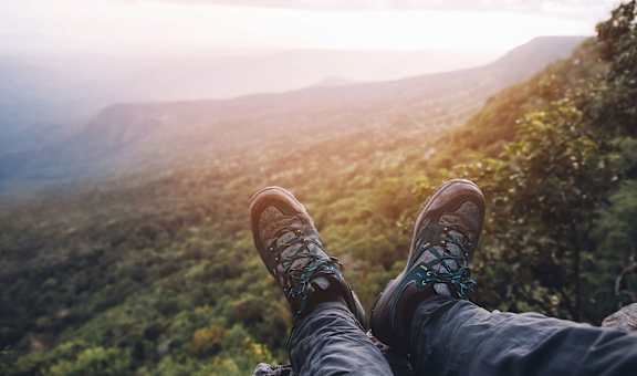 a person sitting on a rock looking out over a mountainous landscape
