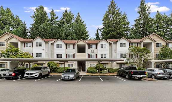 a parking lot in front of an apartment building with cars parked in front