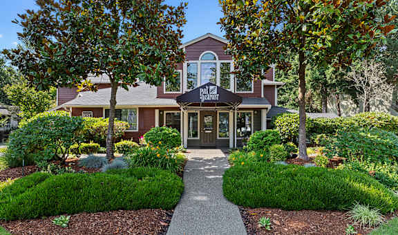 the front of a house with a walkway and trees