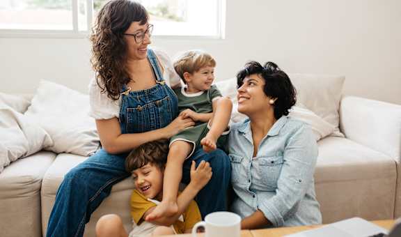 a mother and father sit on a couch with their children