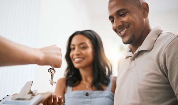 A person is handing over a set of keys to a woman.