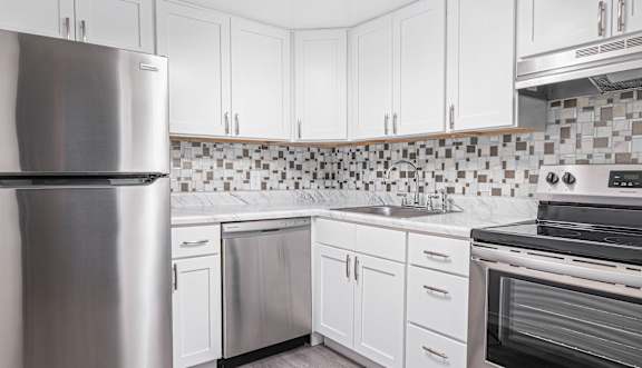Renovated kitchen with white cabinets and stainless steel appliances at Aspen Grove Apartment Homes in Warminster, PA