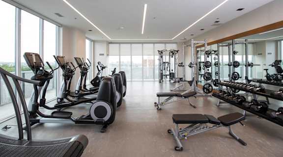 a gym with a lot of exercise equipment and a large window