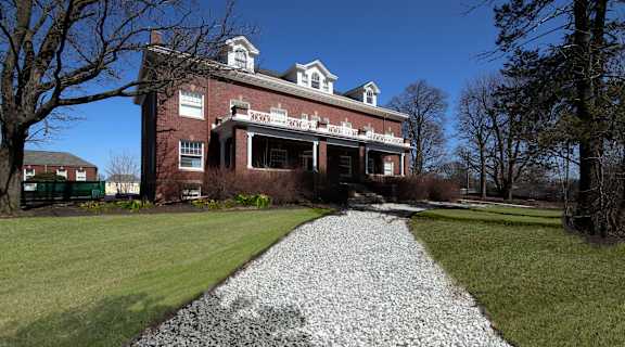 an old brick house with a gravel pathway in front of it