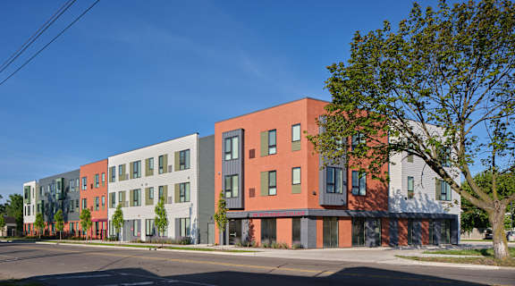 A row of modern buildings with a tree in front of the first one.