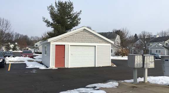 A small house with a red door is surrounded by a parking lot.
