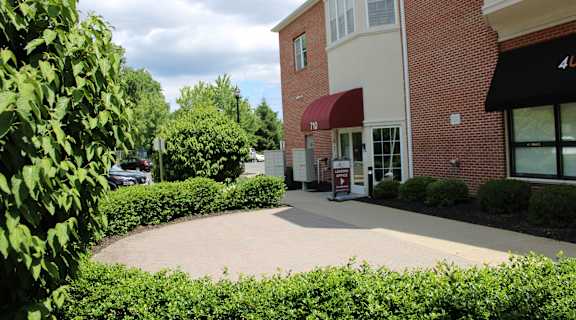 the exterior of a building with a sidewalk and bushes