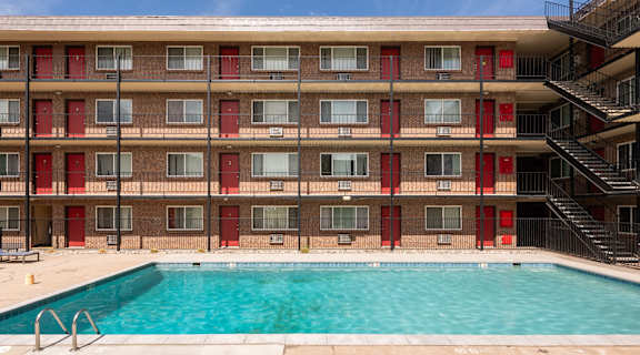 the pool is in front of a red brick building with a swimming pool