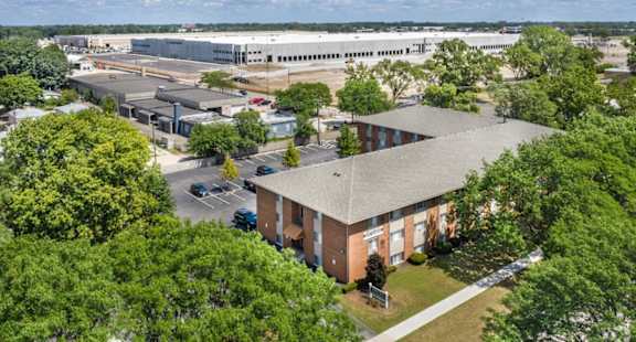 an aerial view of a brick building with trees and a parking lot